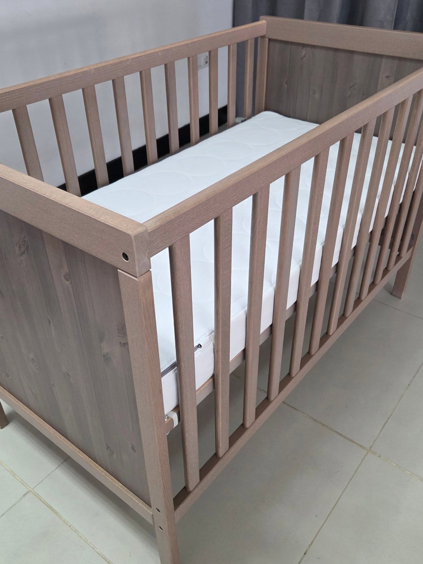 Cuna de madera clara con colchón blanco en un ambiente moderno. Ideal para bebés, combina diseño funcional y seguridad.